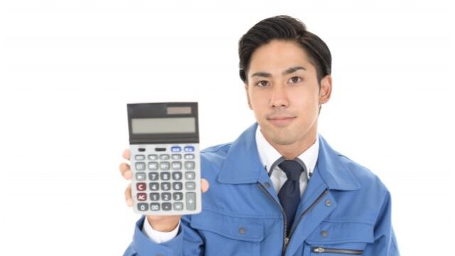 電卓を持つ作業服を着た男性の画像